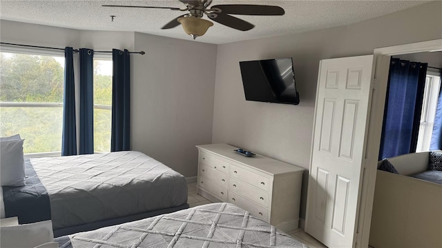 bedroom with a textured ceiling, a ceiling fan, and baseboards