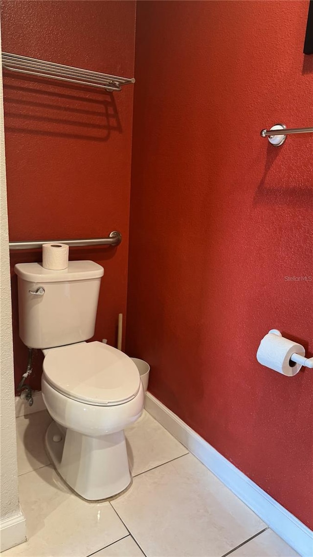 bathroom with baseboards, toilet, and tile patterned floors