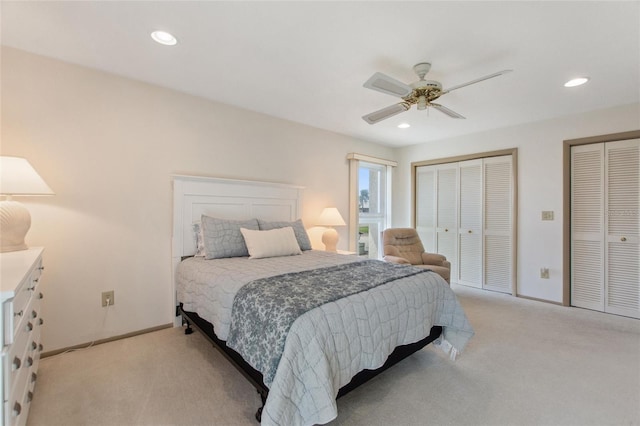 bedroom with recessed lighting, light colored carpet, baseboards, and two closets