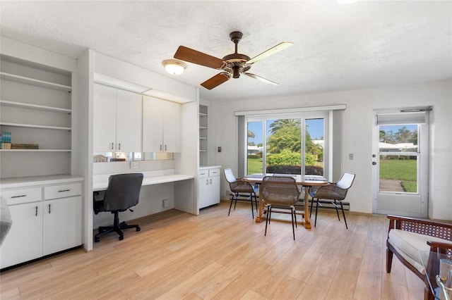 home office with built in desk, light wood-style flooring, and a healthy amount of sunlight