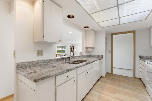 kitchen featuring light stone counters, recessed lighting, a sink, light wood-type flooring, and white appliances