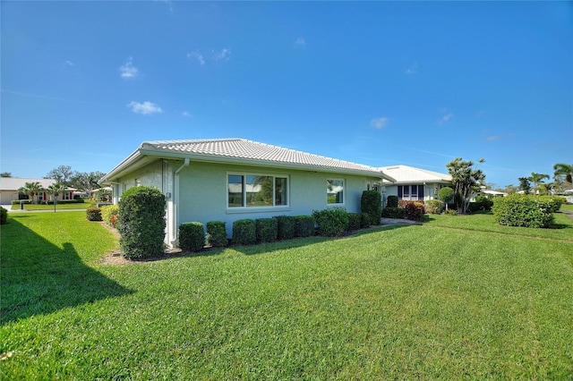 view of side of property with a tiled roof, a lawn, and stucco siding