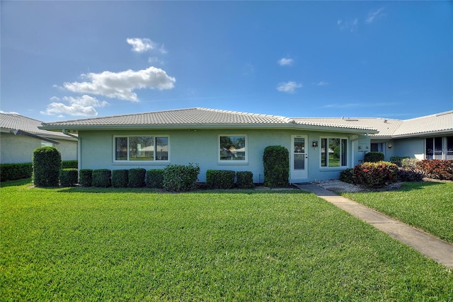 ranch-style house with stucco siding, a tile roof, and a front yard