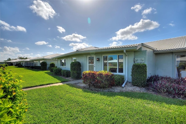 ranch-style home with stucco siding, a front lawn, and a tiled roof