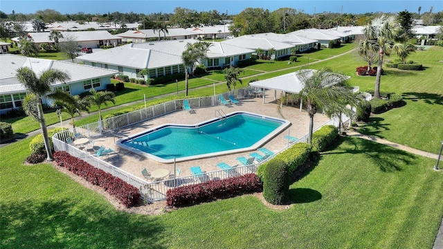 community pool featuring a fenced backyard, a residential view, and a lawn