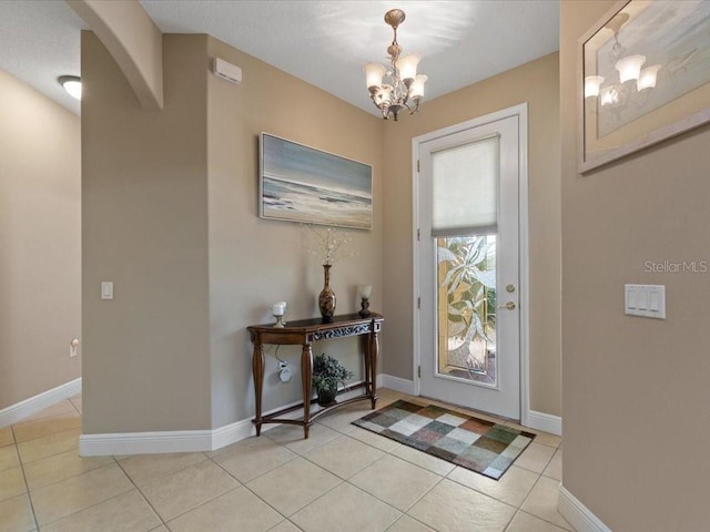 entrance foyer with light tile patterned floors, a notable chandelier, arched walkways, and baseboards