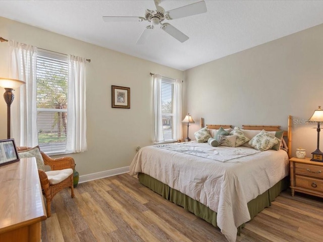 bedroom with a ceiling fan, baseboards, and wood finished floors