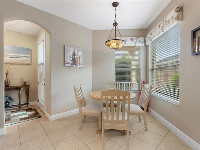 dining space with arched walkways, baseboards, and light tile patterned flooring