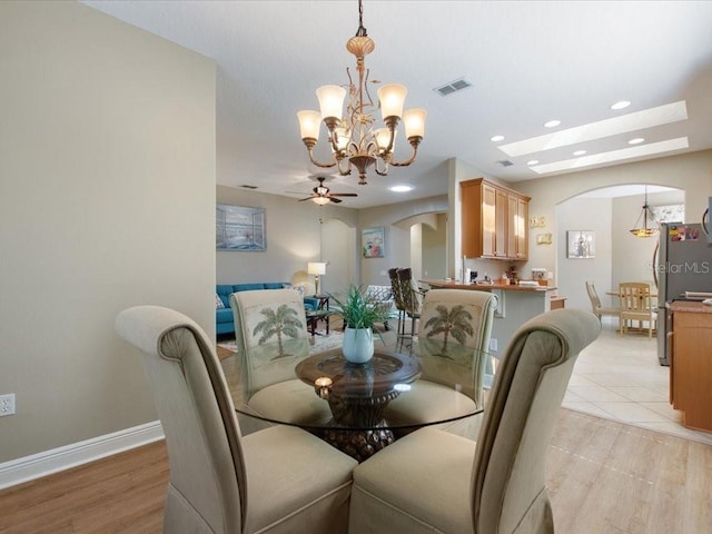 dining space with visible vents, arched walkways, baseboards, and light wood-style flooring