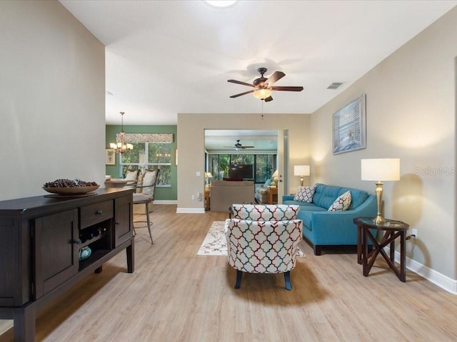 living area with visible vents, baseboards, ceiling fan with notable chandelier, and light wood finished floors