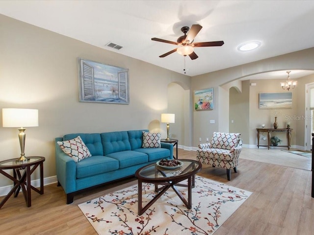 living area with visible vents, arched walkways, light wood-style floors, baseboards, and ceiling fan