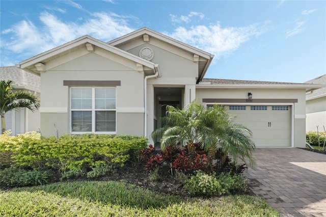 single story home with stucco siding, decorative driveway, and a garage