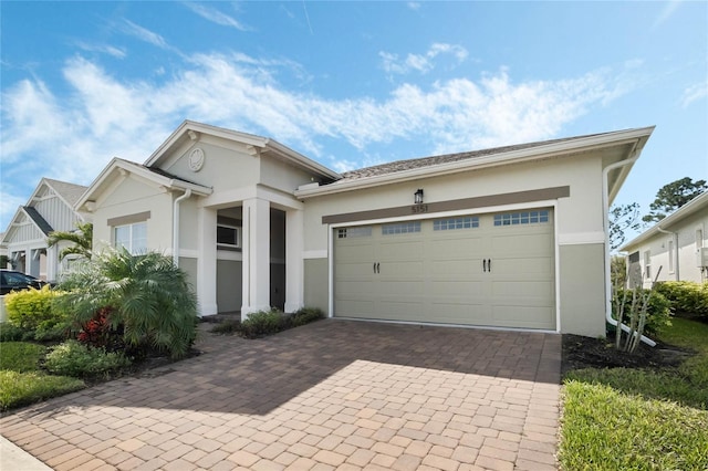 view of front facade featuring stucco siding, decorative driveway, and a garage