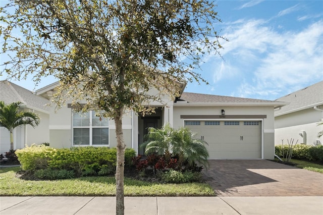 view of front of home with stucco siding, decorative driveway, and a garage