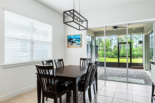 tiled dining space with a ceiling fan, baseboards, and a sunroom