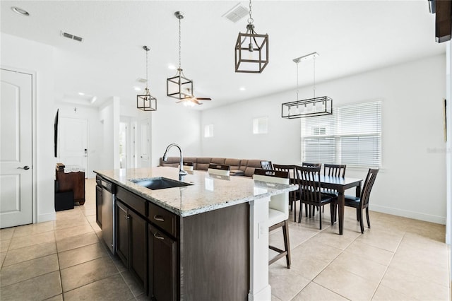 kitchen with light tile patterned floors, visible vents, a sink, a kitchen bar, and decorative light fixtures