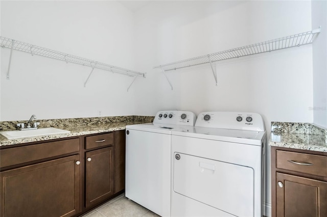 laundry area featuring washing machine and clothes dryer, cabinet space, light tile patterned flooring, and a sink