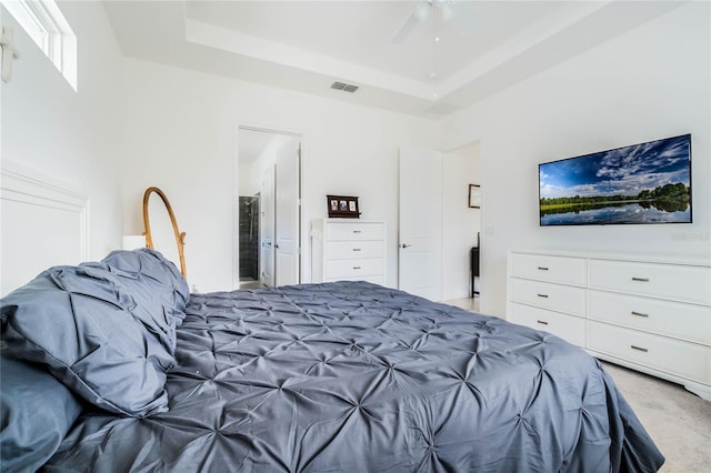 carpeted bedroom with visible vents, a raised ceiling, ceiling fan, and ensuite bathroom