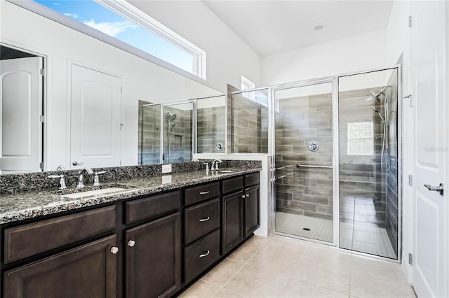 bathroom featuring tile patterned flooring, a shower stall, double vanity, and a sink