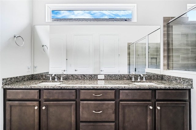 full bathroom featuring double vanity, tiled shower, and a sink