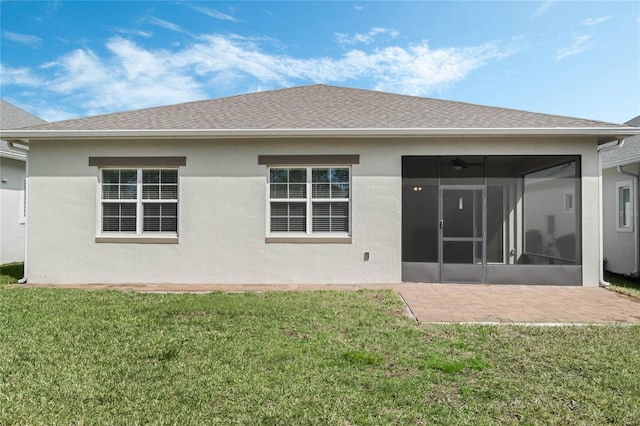 rear view of property with a yard, a patio area, a shingled roof, and a sunroom