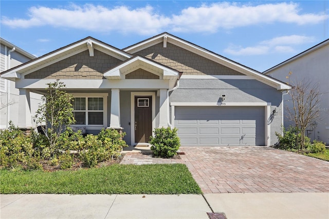 view of front facade with decorative driveway, an attached garage, and stucco siding