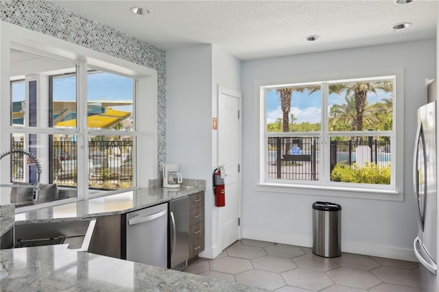 7793 Clove Hitch Way, Orlando, FL 32832 - kitchen with baseboards, stainless steel appliances, a textured ceiling, and light stone countertops