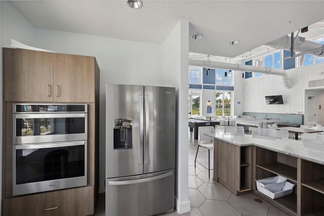 7793 Clove Hitch Way, Orlando, FL 32832 - kitchen with light tile patterned floors, light stone counters, a high ceiling, appliances with stainless steel finishes, and open shelves