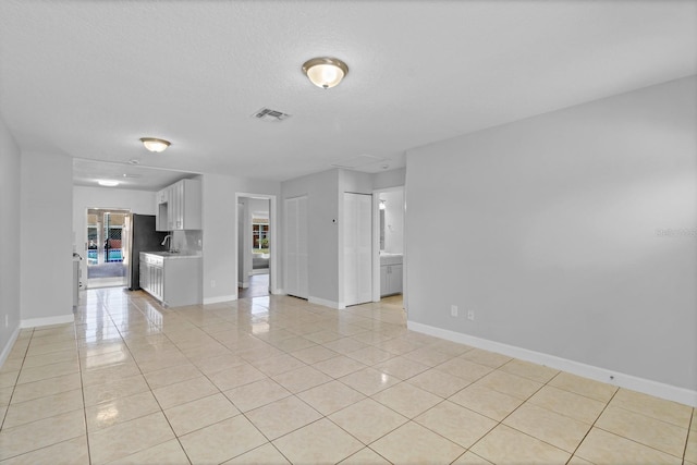 unfurnished living room featuring visible vents, baseboards, and light tile patterned floors