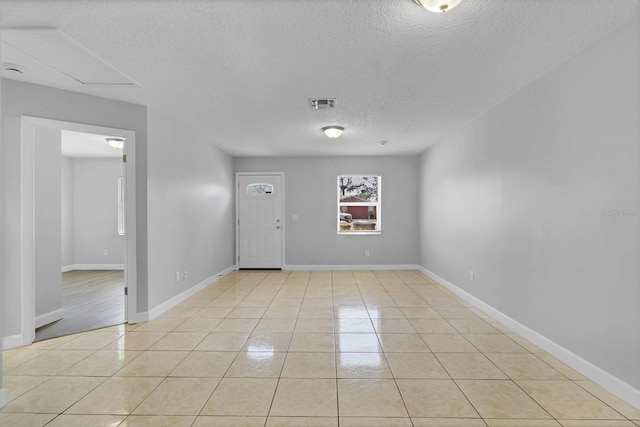 entrance foyer featuring a textured ceiling, light tile patterned flooring, visible vents, and baseboards