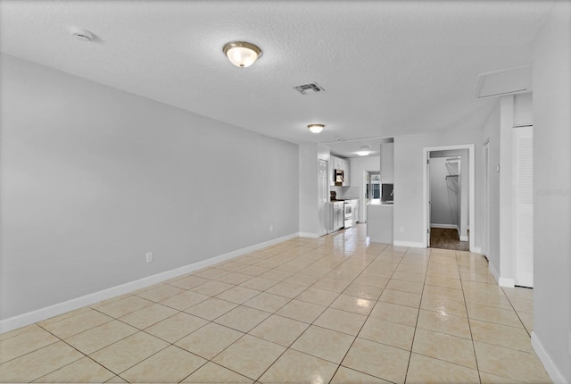 spare room featuring visible vents, a textured ceiling, baseboards, and light tile patterned floors