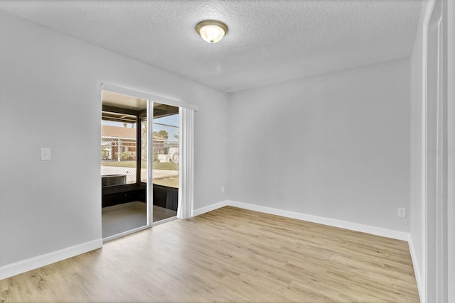 spare room featuring a textured ceiling, wood finished floors, and baseboards