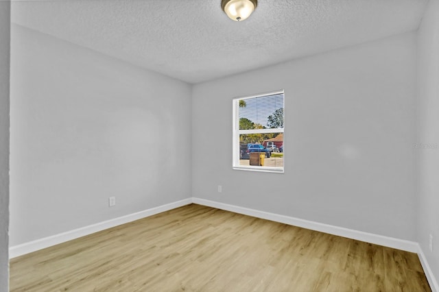 unfurnished room featuring a textured ceiling, baseboards, and wood finished floors