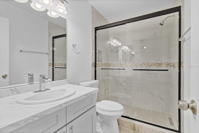 bathroom with a marble finish shower, vanity, and toilet