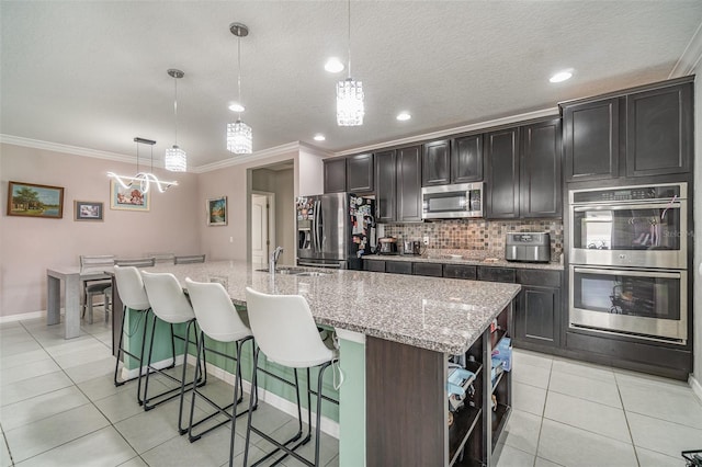 kitchen featuring light tile patterned floors, stainless steel appliances, tasteful backsplash, a kitchen island with sink, and a kitchen breakfast bar