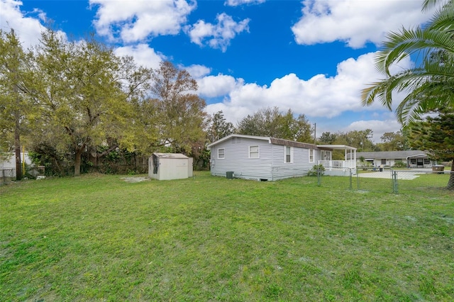 view of yard featuring a storage shed, fence, and an outbuilding