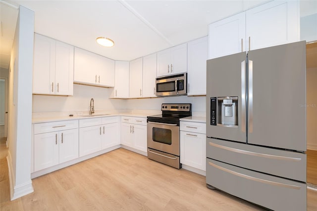 kitchen featuring a sink, white cabinets, light countertops, appliances with stainless steel finishes, and light wood finished floors