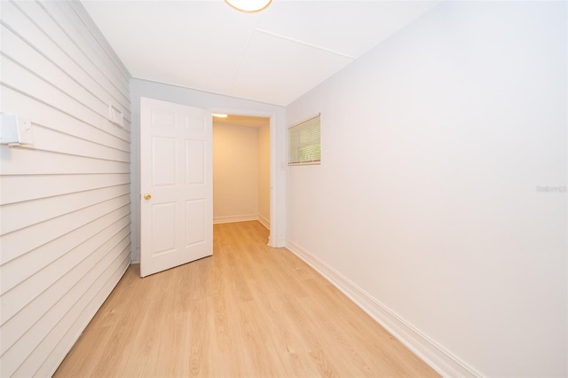 corridor featuring light wood-type flooring and baseboards