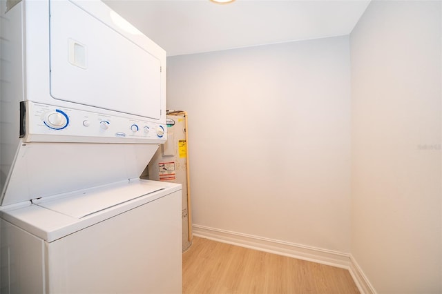 laundry room featuring stacked washer and dryer, water heater, light wood-style floors, and baseboards