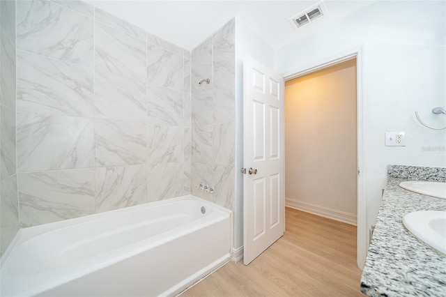 bathroom with shower / bath combination, visible vents, vanity, wood finished floors, and baseboards