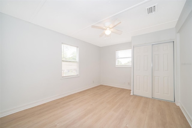 unfurnished bedroom with baseboards, a closet, visible vents, and light wood-style floors