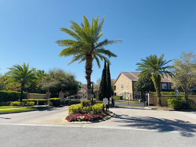 view of street with a gate, sidewalks, curbs, and a gated entry