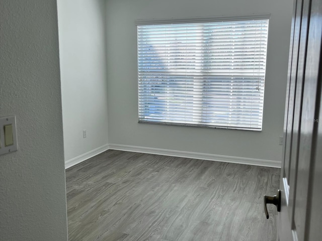 spare room with baseboards and wood finished floors