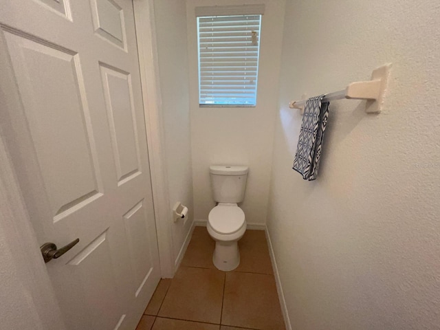 bathroom featuring tile patterned flooring, toilet, and baseboards