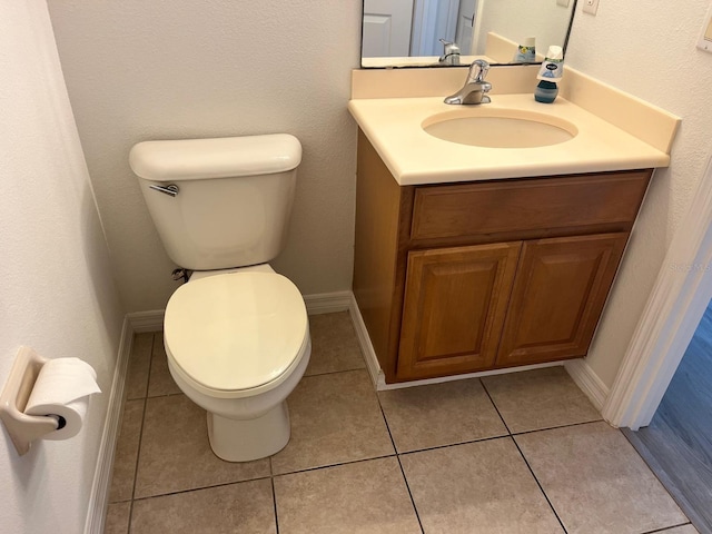 bathroom featuring toilet, tile patterned flooring, baseboards, and vanity