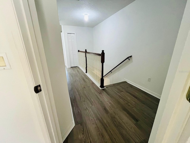 staircase with a textured ceiling, baseboards, and wood finished floors