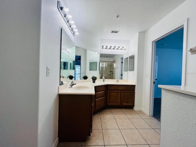 full bathroom with visible vents, a sink, a shower stall, a textured ceiling, and tile patterned floors