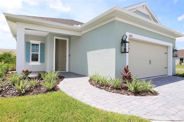 view of front of property with a garage, decorative driveway, a shingled roof, and stucco siding