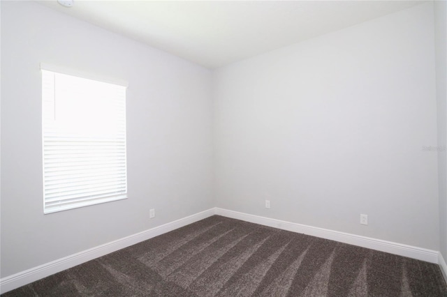 unfurnished room with dark carpet and baseboards