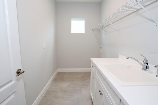 clothes washing area featuring hookup for a washing machine, cabinet space, a sink, and baseboards